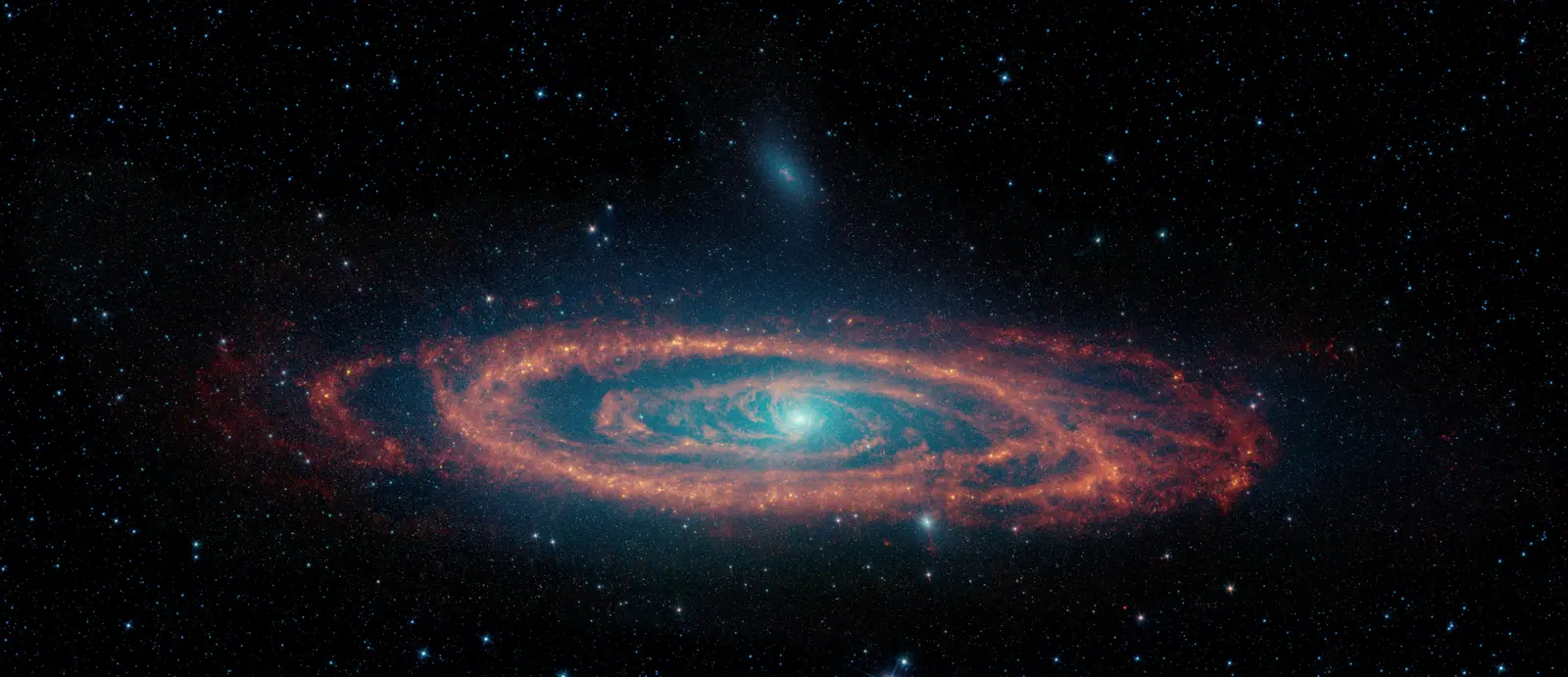 The Andromeda galaxy seen in infrared, a tilted spiral with a glowing blue core and rings of orange dust, surrounded by stars