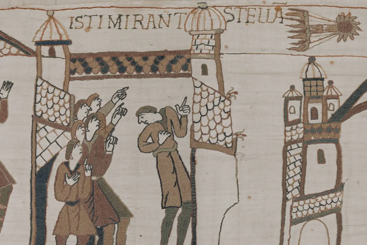 Embroidered scene from the Bayeux Tapestry: figures pointing up at Halley's Comet, shown as a fiery star with a long tail, with the Latin words ISTI MIRANT STELLA above