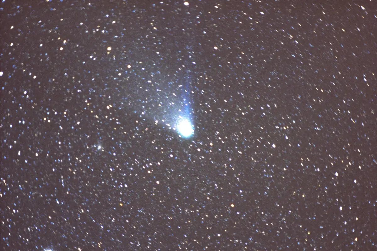 Halley's Comet in 1986 as a bright blue-white head with a thin blue tail among thousands of stars