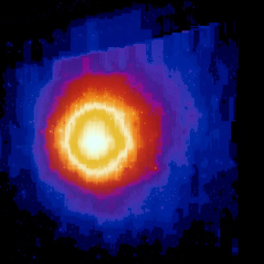 False-color image of Halley's Comet's hydrogen cloud, a glowing yellow-white core surrounded by orange, purple and blue halos