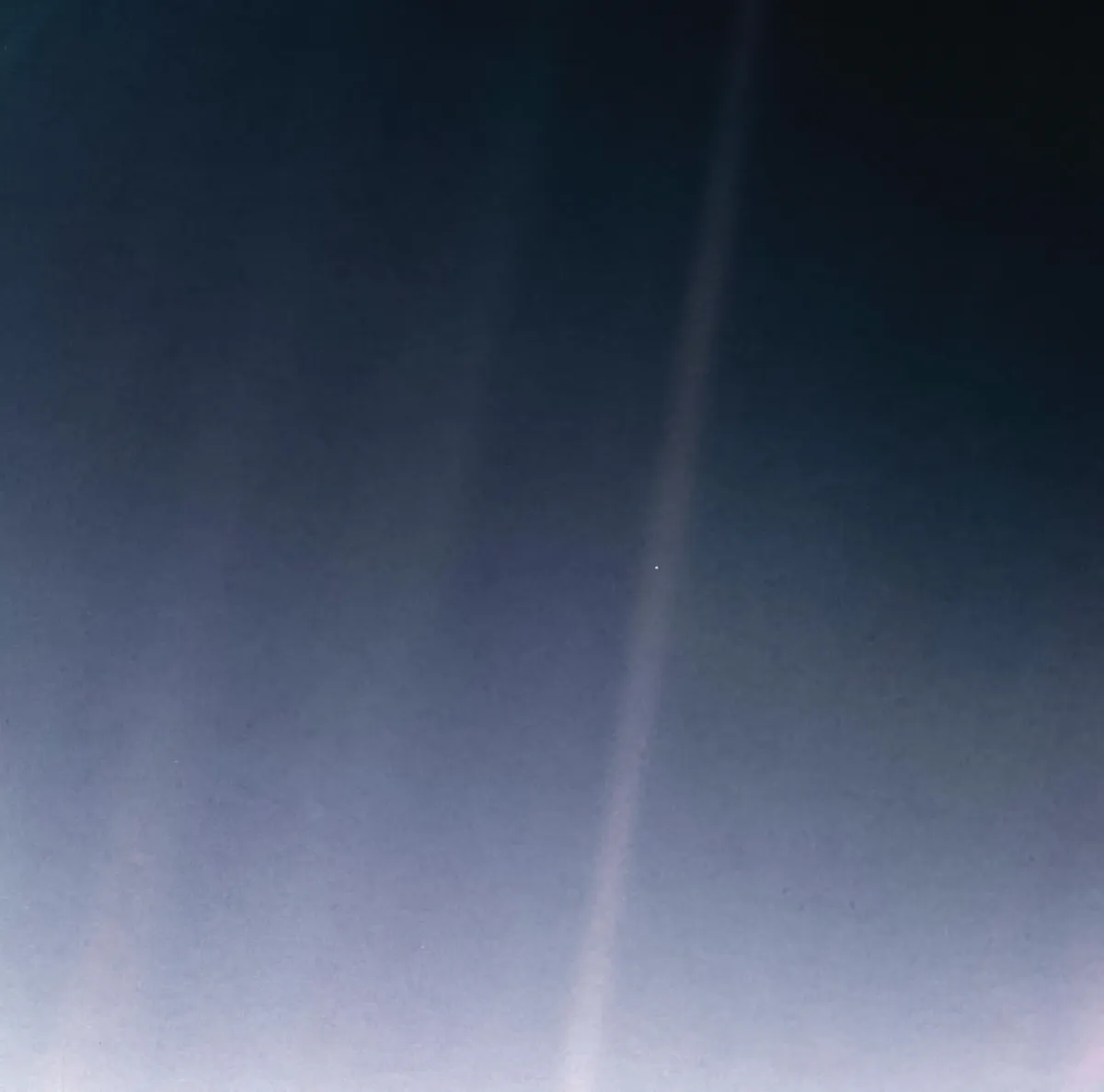 Earth as a tiny bluish dot inside a pale beam of scattered sunlight, seen by Voyager 1
